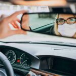 Femme d'affaires avec un masque de protection, assise dans une voiture.