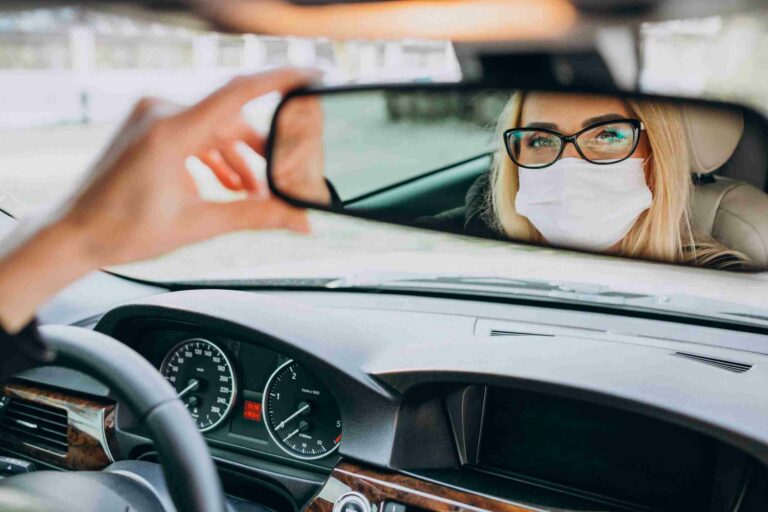 Femme d'affaires avec un masque de protection, assise dans une voiture.