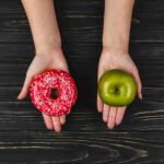 Deux mains proposant un donuts ou une pomme