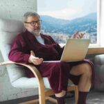 vieille homme assis avec son ordinateur sur les genoux