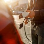 homme tenant un chargeur de voiture électrique