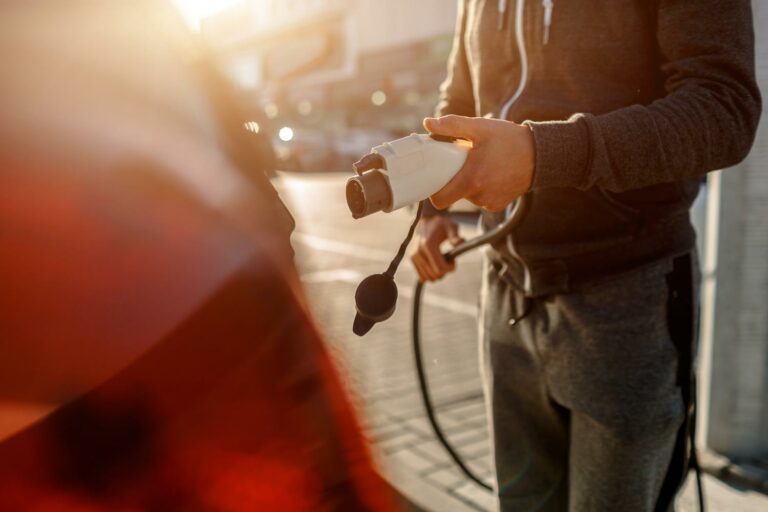 homme tenant un chargeur de voiture électrique